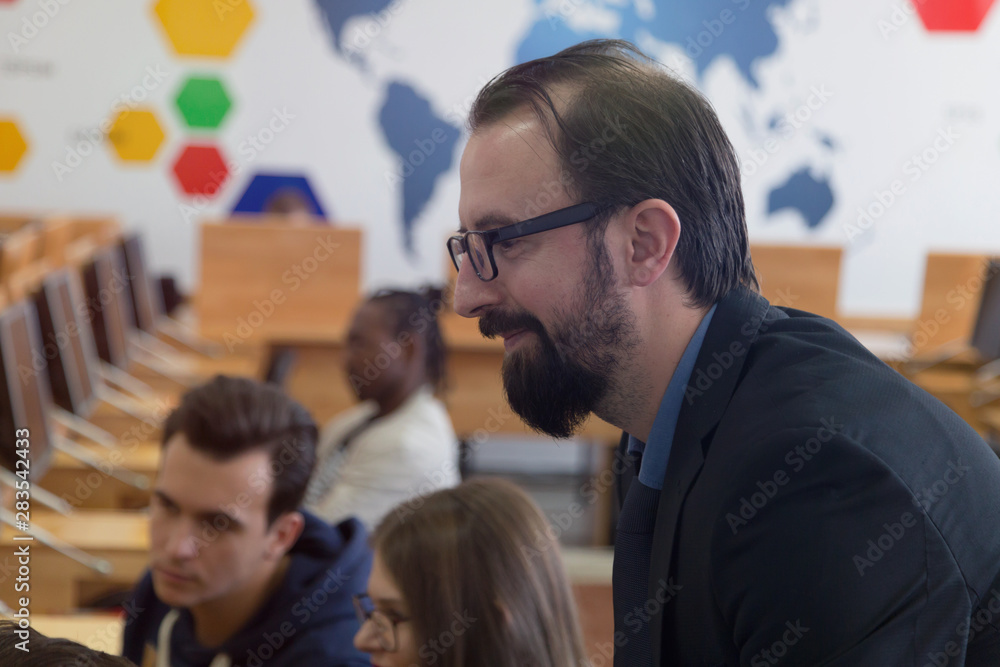 Male professor explain lesson to students and interact with them in the classroom.Helping a students during class. Male professor explain lesson to students and interact with them in the classroom.Helping a students during class.