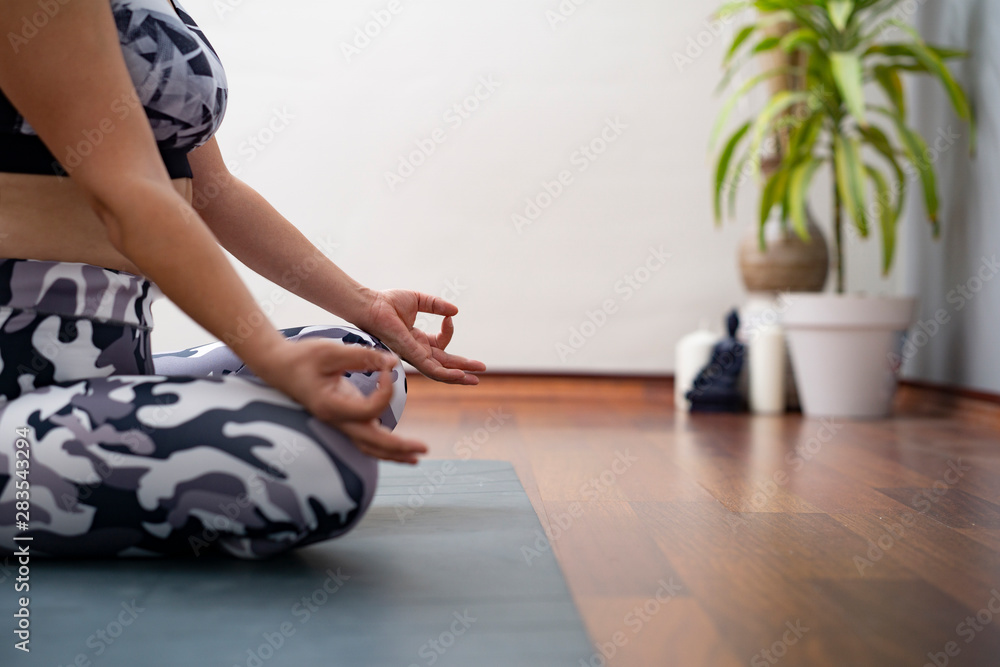 Fototapeta premium woman sitting on the floor and doing meditation at yoga class