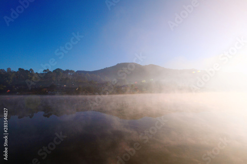 Beautiful landscape heaven of mist and fog over the lake and sunrise shining with blue sky reflection on the water surface at Hill tribe village on mountain in Thailand © cocorattanakorn