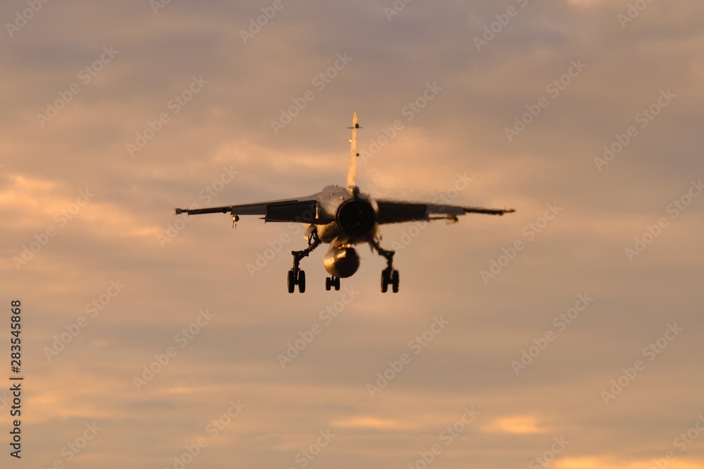 Avión de combate Mirage F1 aterrizando al anochecer Avión de combate Mirage F1 aterrizando al anochecer