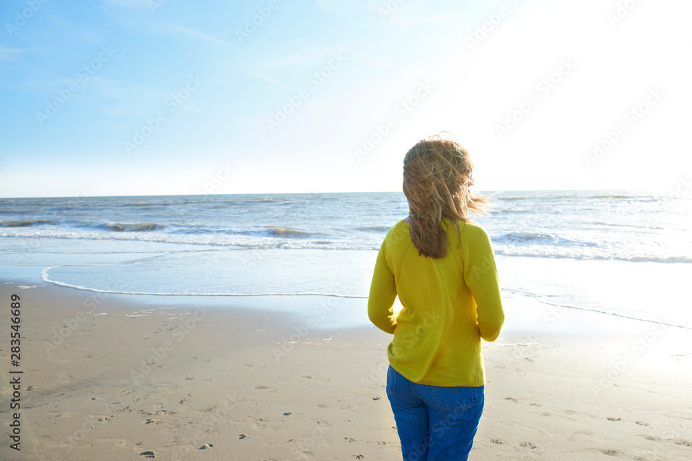Woman standing lonely on the beach and looking at the sea Woman standing lonely on the beach and looking at the sea
