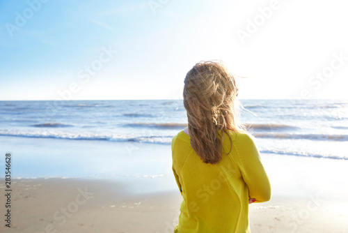 Sticker Woman standing lonely on the beach and looking at the sea