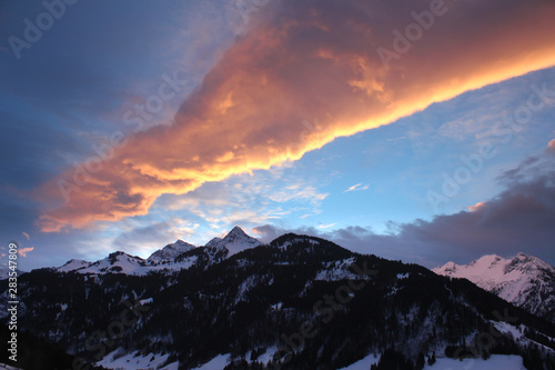 Magical colorful sunrise with a unique cloud constellation over snow-covered peaks in the alps.