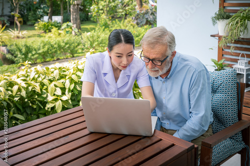 Bilde på lerret Caregiver assist senoir eldery man using notebook laptop computer connect to Int