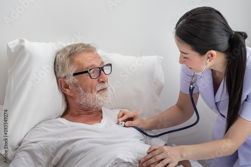 Happy nurse use stethoscope examine elderly man health in bedroom at nursing home