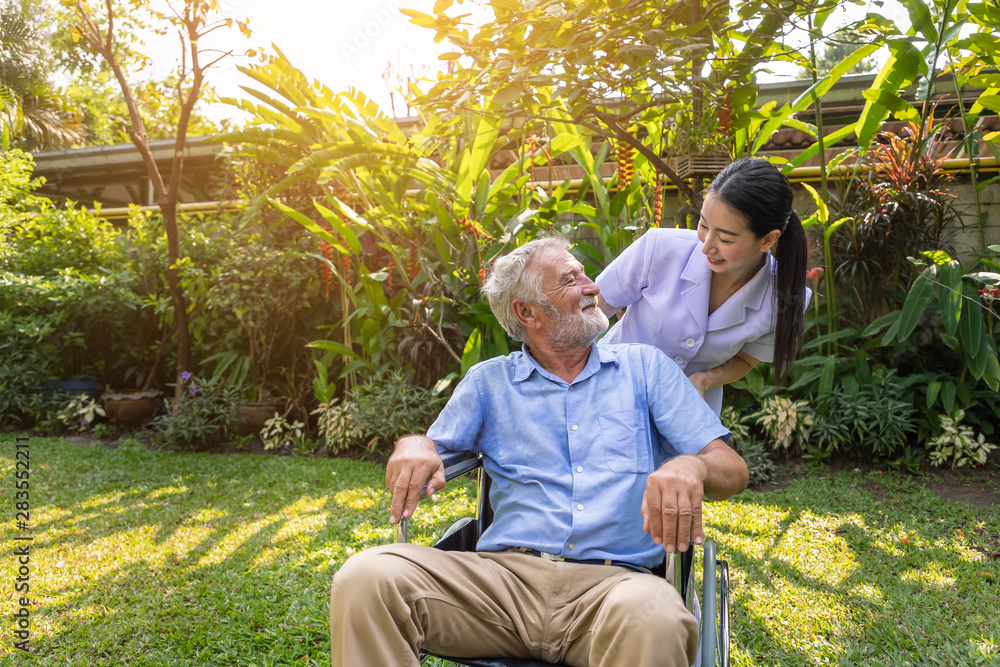 Happy nurse take care elderly man on wheelchair in garden at nursing home Happy nurse take care elderly man on wheelchair in garden at nursing home