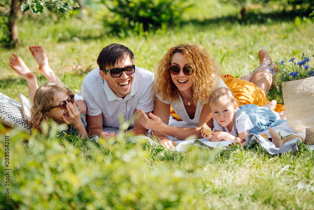 Fototapeta premium Family picnic on grass in the gardens under gentle shade of trees