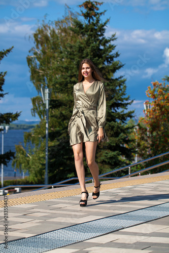 Young beautiful woman in green dress walking on the summer street