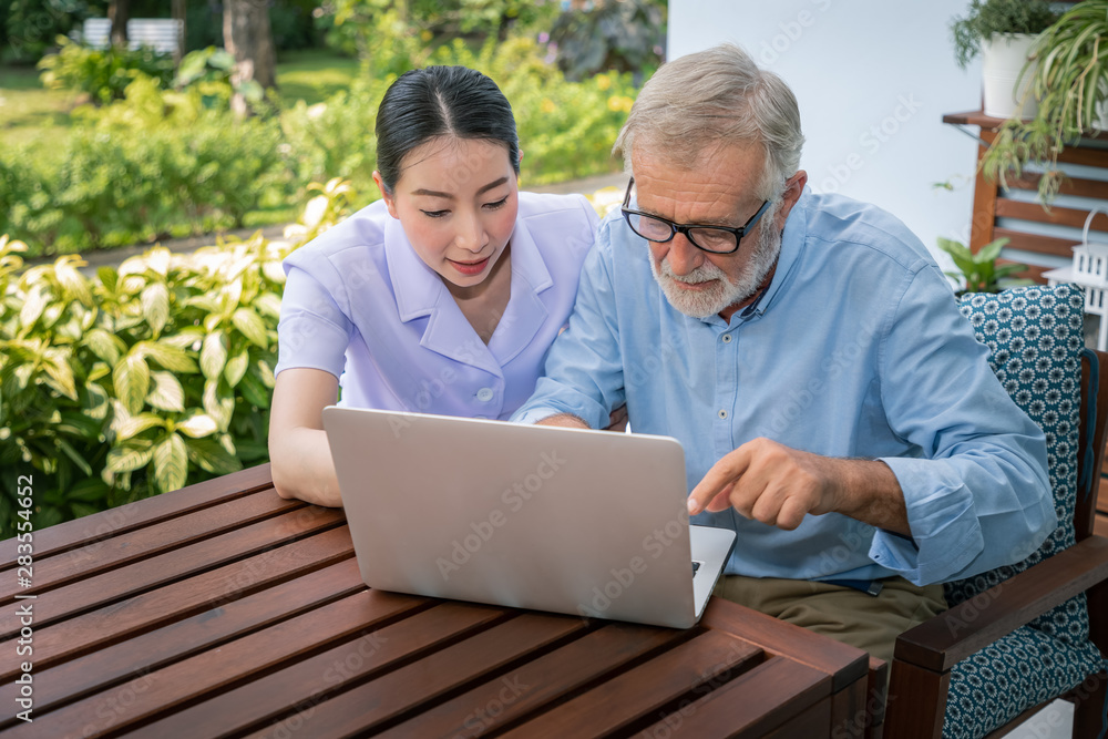 Caregiver assist senoir eldery man using notebook laptop computer connect to Internet