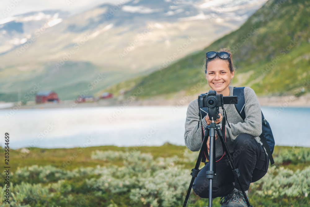 Happy young girl traveler with a camera on the background of a beautiful landscape in Jotunheimen National Park Norway