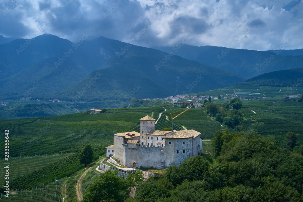 Panoramic view of the Castel Belasi region of Trento north of Italy. The castle is surrounded by nature, vineyards, fruit tree plantations in a quiet location. Aerial view.