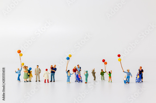 Miniature people holding balloon isolated on white background and copy space for text