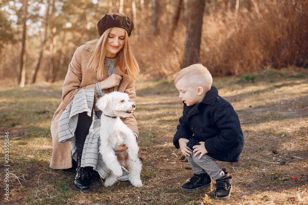 Family in a summer park. Mother in a brown coat. Cute little boy with a dog Family in a summer park. Mother in a brown coat. Cute little boy with a dog