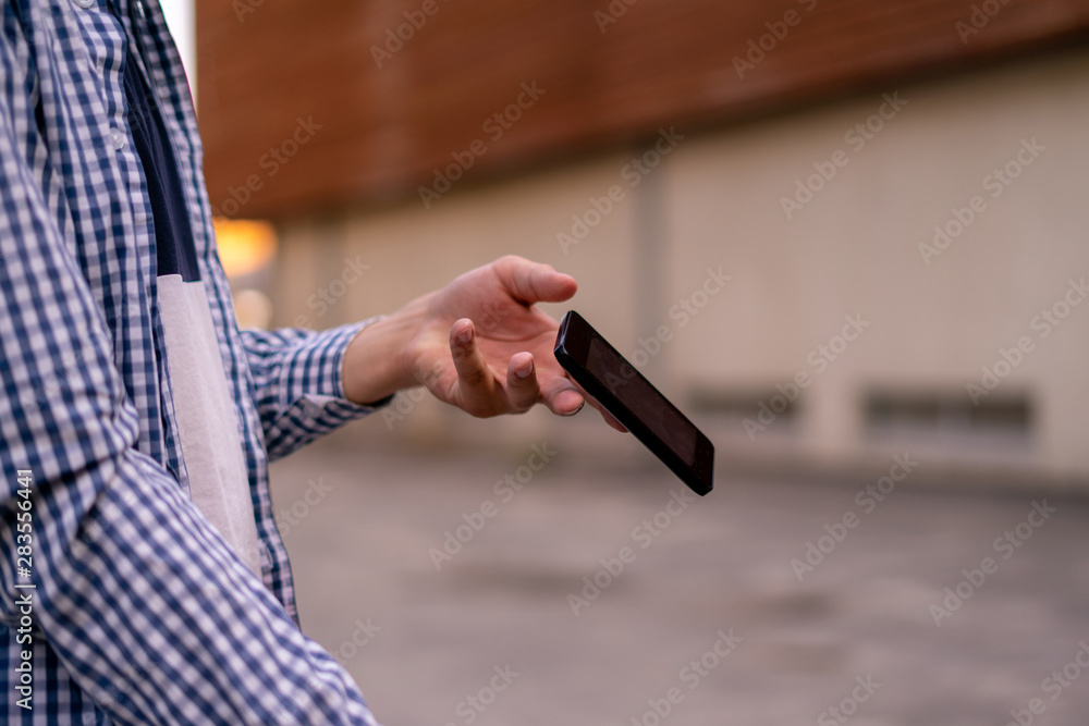 person holding a smartphone in the street, a phone falling and flying  down by an accident - obrazy, fototapety, plakaty 