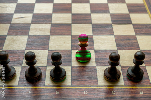 a unique chess pawn in color. leadership concept on a chessboard between other pieces. photo