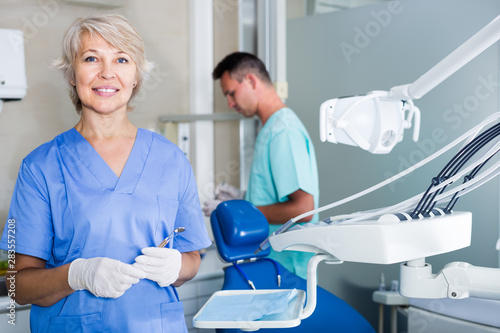 Portrait of mature woman dentist with dental assistant behind