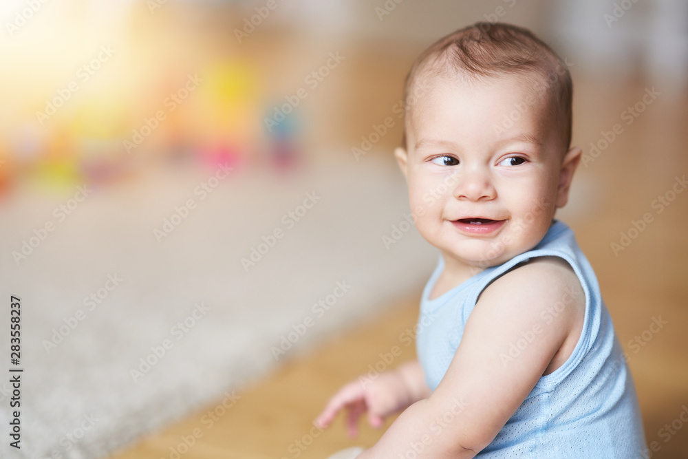 Cute smiling baby boy sitting on floor in living room Cute smiling baby boy sitting on floor in living room