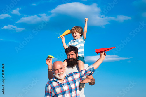 Happy three generations of men have fun and smiling on blue sky background. Father and son playing outdoors. Airplane ready to fly. Cute son with dad playing outdoor.