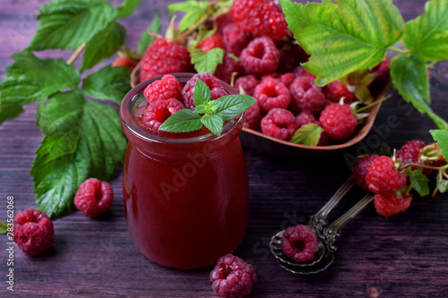 Raspberry jam in glass jar topped with berries and mint