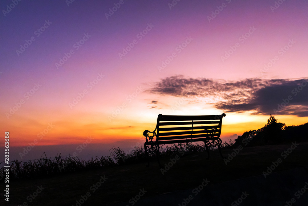 Silhouette of bench against twilight sky over a mountain with copy space. 