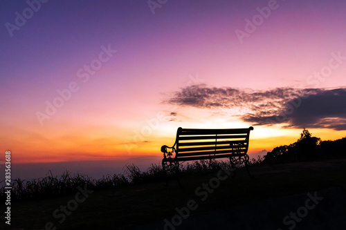 Silhouette of bench against twilight sky over a mountain with copy space. 
