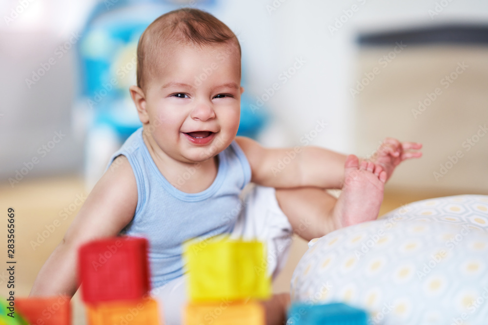 Cute smiling baby boy sitting on floor in living room Cute smiling baby boy sitting on floor in living room
