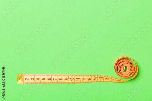 Frame made of measuring tape on green background. Top view of sewing concept. Slim waist concept with empty space for your design photo