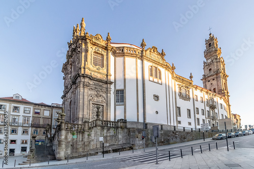 View of the beautiful baroque Church of Clerigos (Igreja dos Clerigos, in Portuguese) and iconic Clerigos Tower, one of the landmarks and symbols of Oporto city in Portugal. Sunset color in blue sky. photo