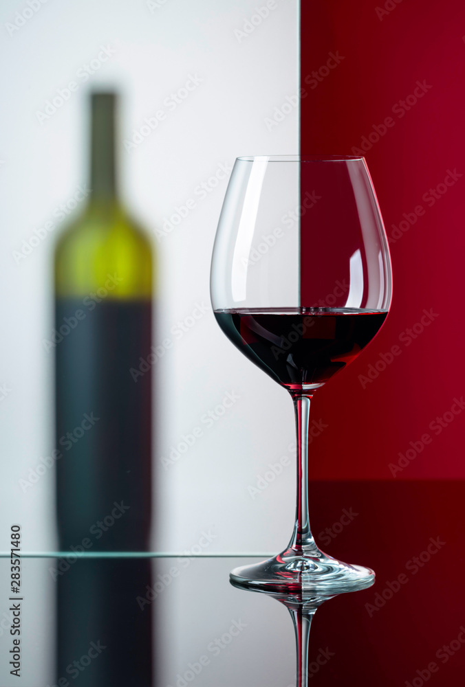 Bottle and glass of red wine on a black reflective background. Bottle and glass of red wine on a black reflective background.