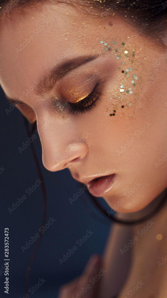 Charming girl with trendy glitter makeup, fashionable make-up with gold  glitter on the cheekbones and near the eyes. Stock Photo | Adobe Stock