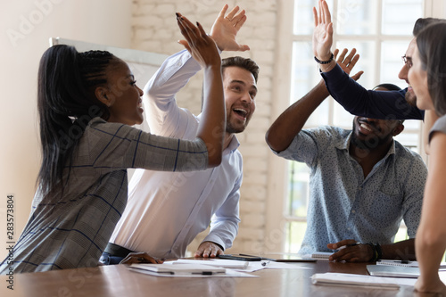 Multiracial euphoric business team people give high five in office photo