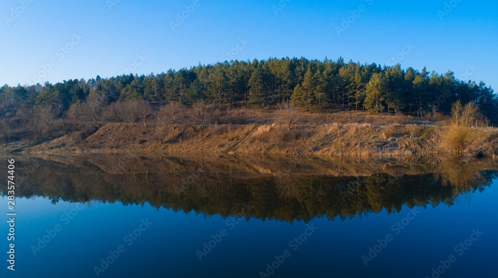 A beautiful forest reflecting in a large lake before it.