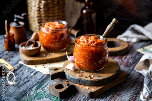 two glass jars with home made red vegetable caviar, ratatouille, ragout on wooden brown boards