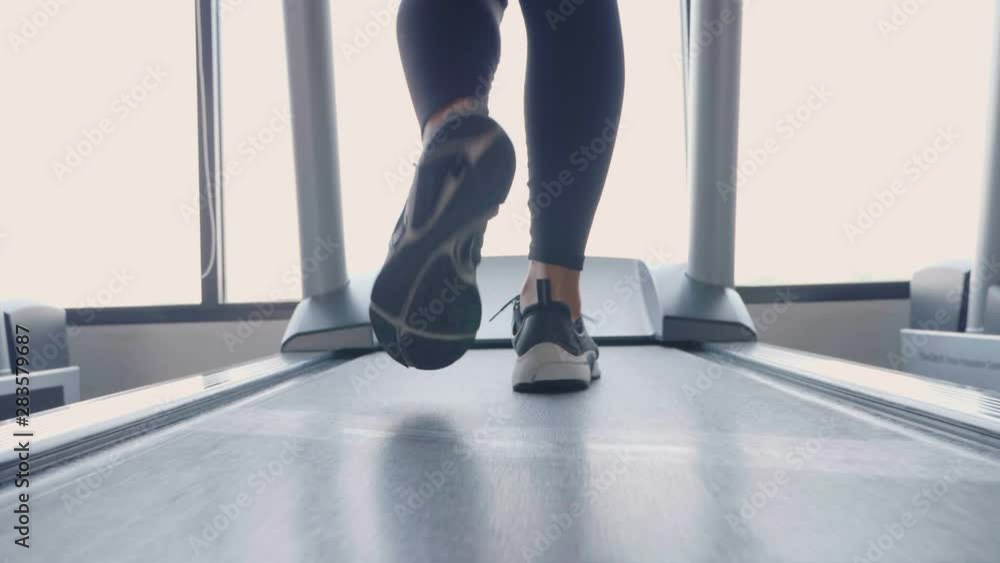 Close up of sporty girl legs in sportswear running and jogging on gym treadmill at the fitness sport gym in slow motion Close up of sporty girl legs in sportswear running and jogging on gym treadmill at the fitness sport gym in slow motion