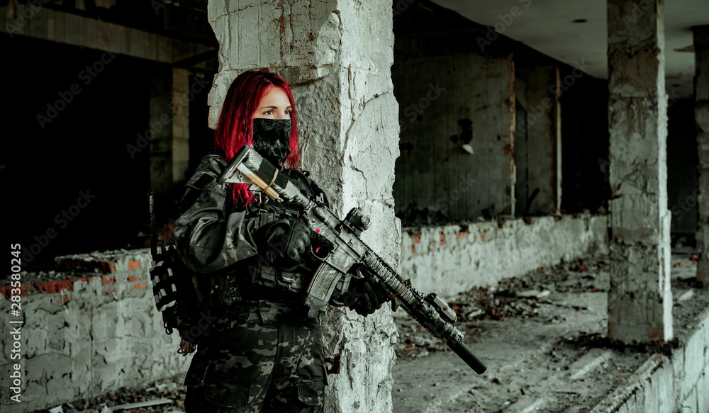 Airsoft red-head woman in uniform and put down machine gun. Close up soldier standing on balkony. Horizontal photo Airsoft red-head woman in uniform and put down machine gun. Close up soldier standing on balkony. Horizontal photo