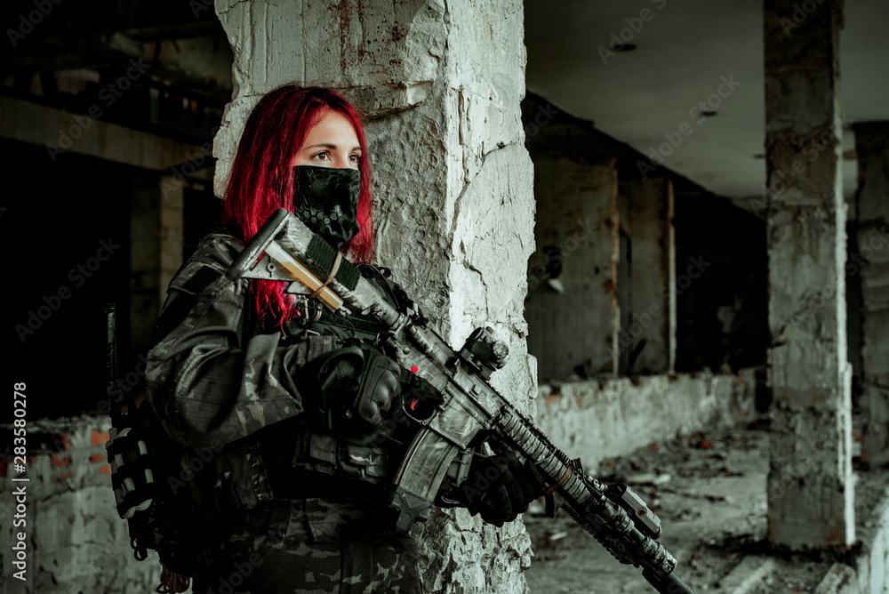 Airsoft red-head woman in uniform and put down machine gun. Close up soldier standing on balkony. Horizontal photo side view Airsoft red-head woman in uniform and put down machine gun. Close up soldier standing on balkony. Horizontal photo side view