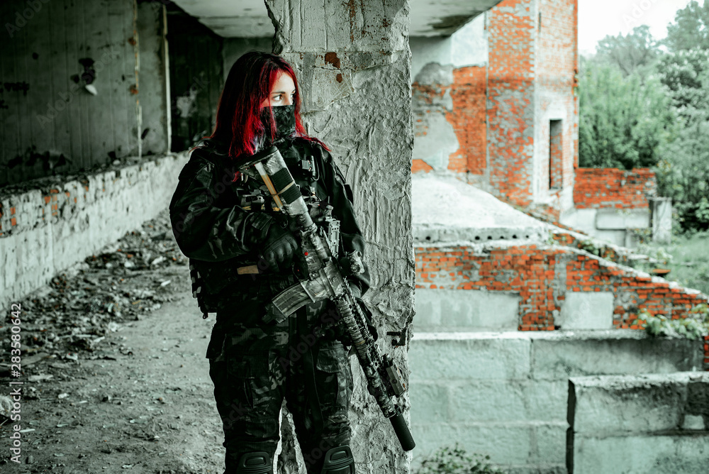Airsoft red-head woman in uniform and put down machine gun. Soldier standing on balkony. Horizontal photo Airsoft red-head woman in uniform and put down machine gun. Soldier standing on balkony. Horizontal photo