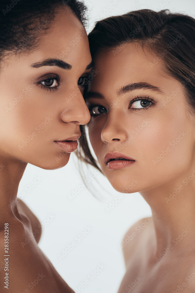 two attractive multiethnic young women looking away isolated on grey two attractive multiethnic young women looking away isolated on grey