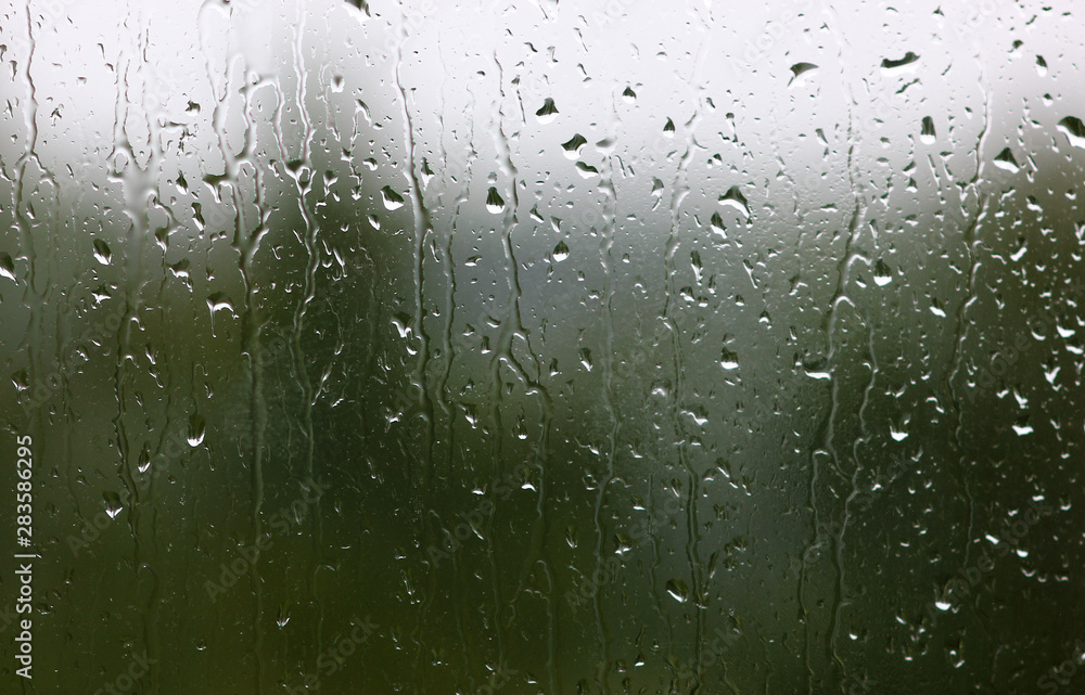 dripping down the glass raindrops outside the window with a blurred background dripping down the glass raindrops outside the window with a blurred background