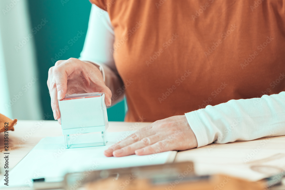 Fototapeta premium Self employed female carpenter is stamping project documentation