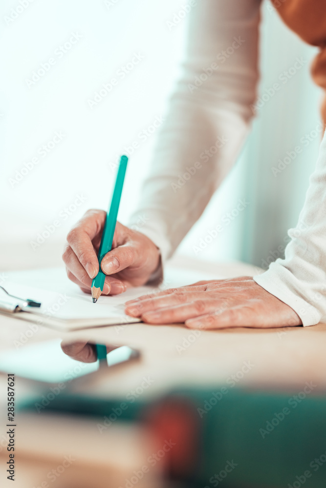 Female carpenter writing project notes in woodwork workshop