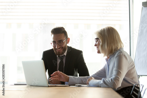 Mature businesswoman mentor helping new employee with corporate software