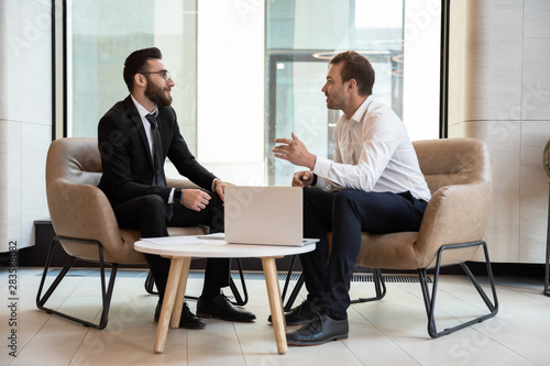 Confident businessmen discussing deal at meeting in modern office