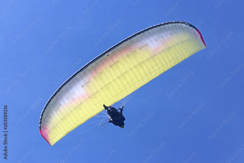 Tandem Paraglider flying yellow wing Tandem Paraglider flying yellow wing