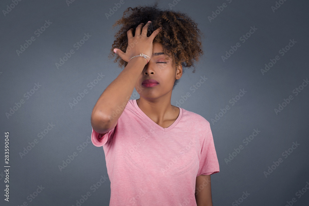 Frustrated African woman wearing casual clothes holding hand on forehead being depressed regretting what she done having headache. Confused female with frowned face looking stressful having pain Frustrated African woman wearing casual clothes holding hand on forehead being depressed regretting what she done having headache. Confused female with frowned face looking stressful having pain