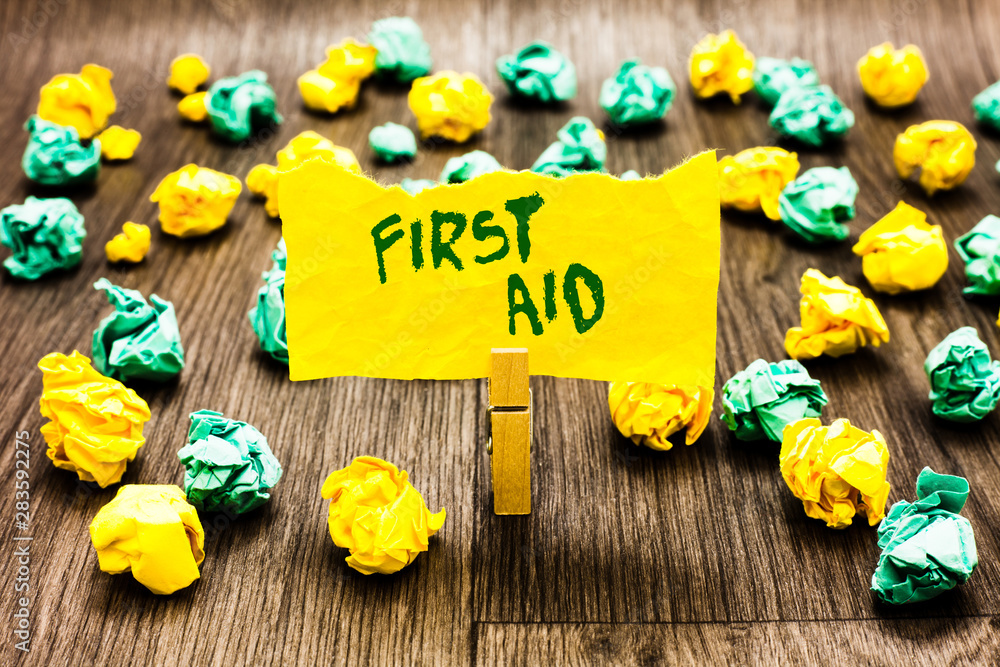 Fototapeta premium Writing note showing First Aid. Business photo showcasing Practise of healing small cuts that no need for medical training Clothespin holding yellow note paper crumpled papers several tries