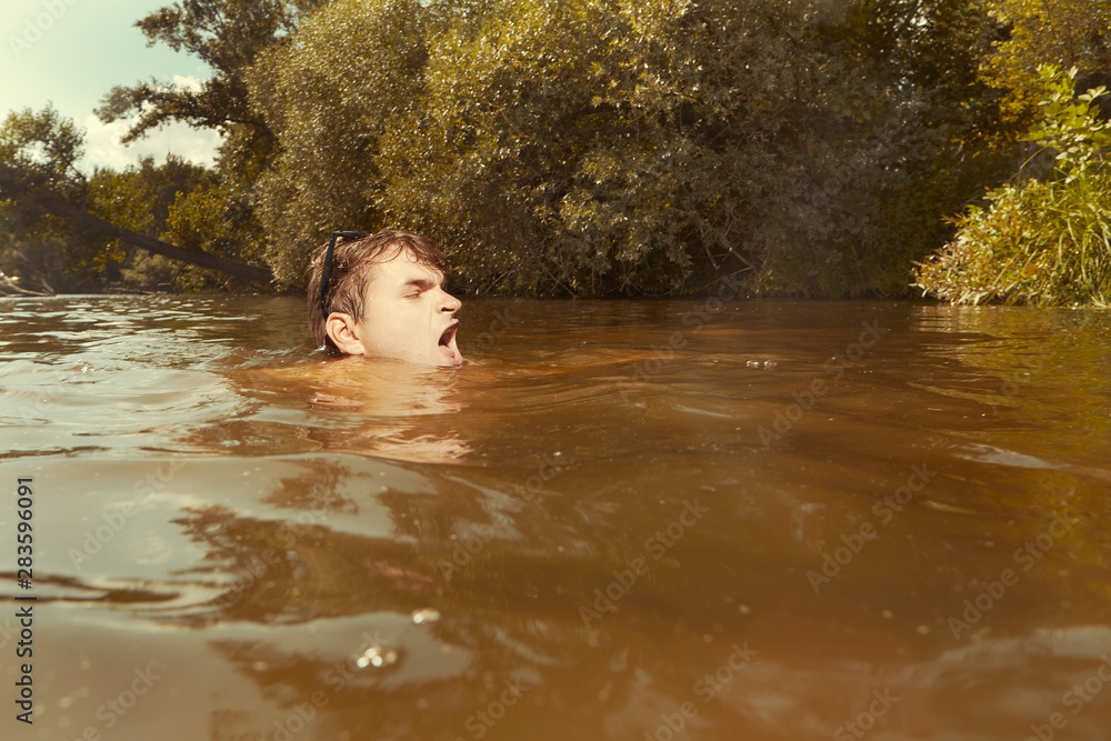 Fototapeta premium Funny man in sunglasses swimming in lake on inner tube