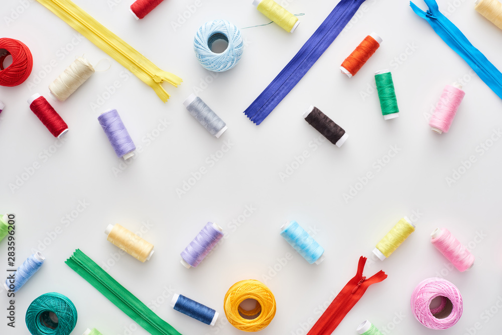 top view of colorful threads, knitting yarn balls and zippers on white background top view of colorful threads, knitting yarn balls and zippers on white background