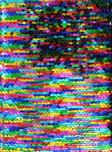 Sequins close-up macro. Abstract background with multicolor sequins on the fabric. Texture scales of round rainbow sequins with color transition.