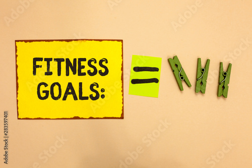 Word writing text Fitness Goals. Business concept for Loose fat Build muscle Getting stronger Conditioning Yellow piece paper reminder equal sign several clothespins sending message